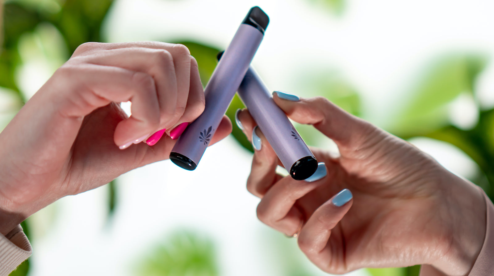 two models toasting with premium vapes in hand on a natural background