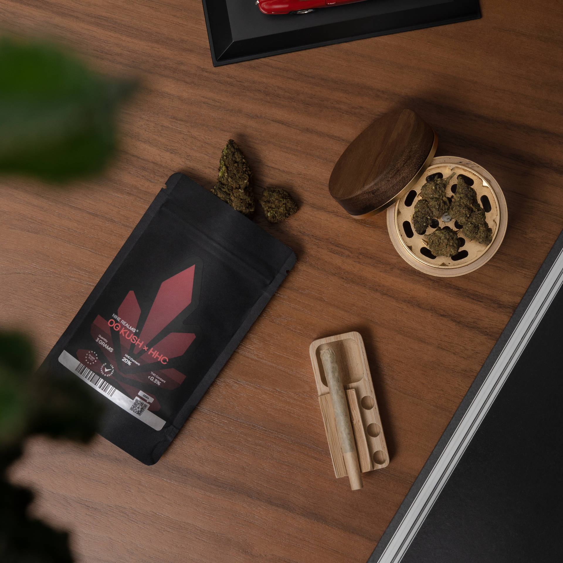 Cannabis flower buds in the grinder with pre-rolled joints on the table